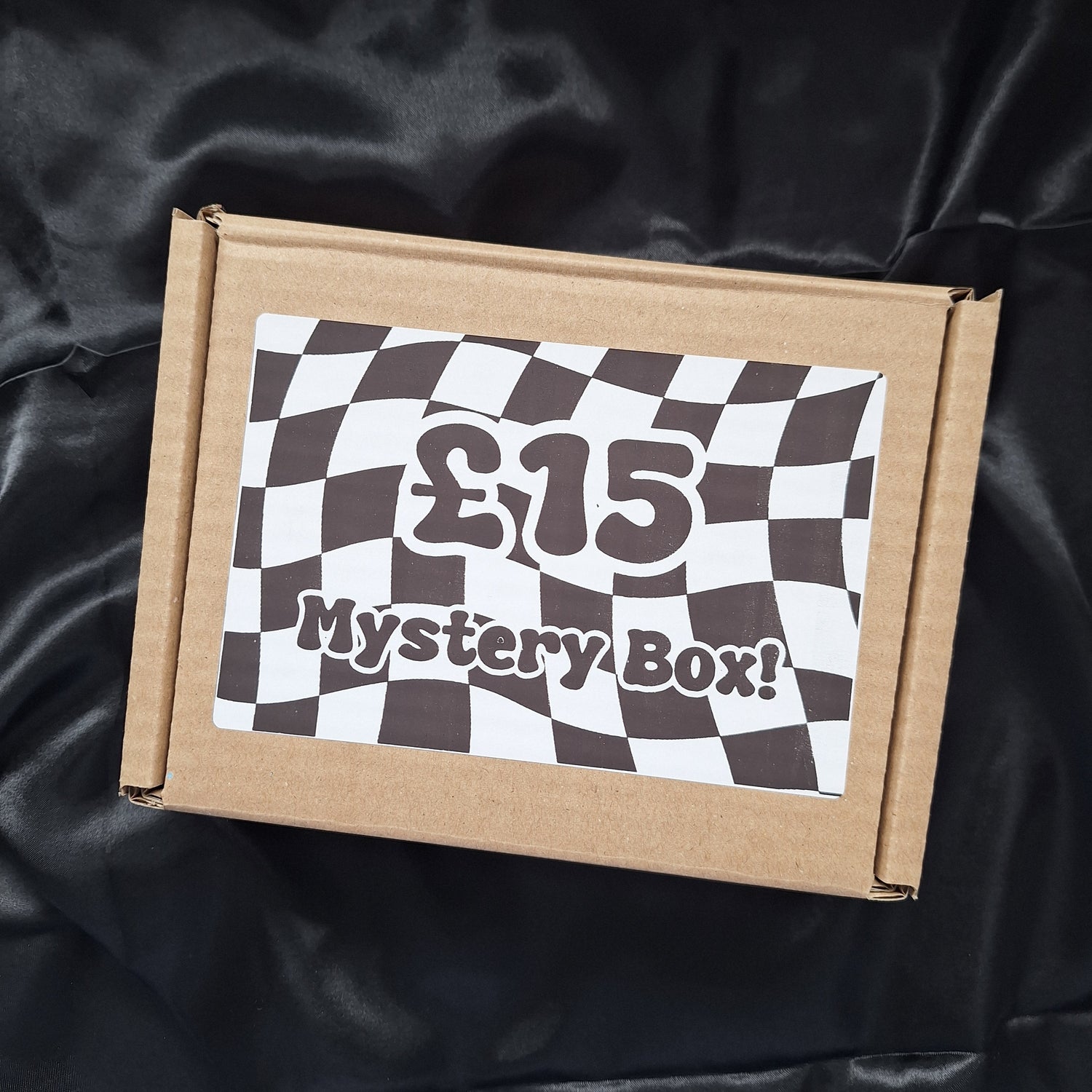 A cardboard mystery box with a checkered pattern label that reads '£15 Mystery Box'.