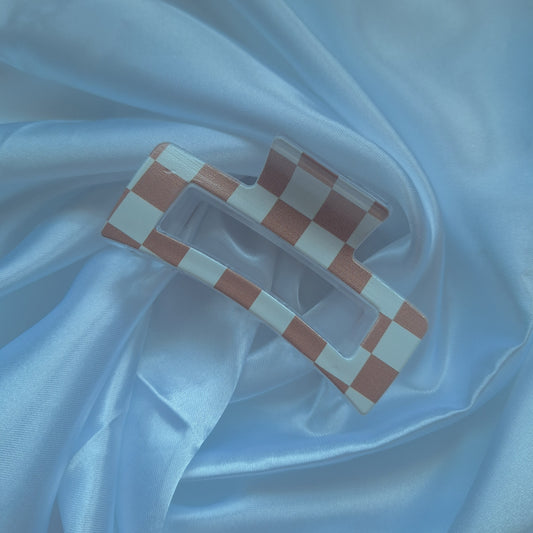 Beige and white checkered acrylic hair claw clip inspired by racing flags displayed on white satin fabric.