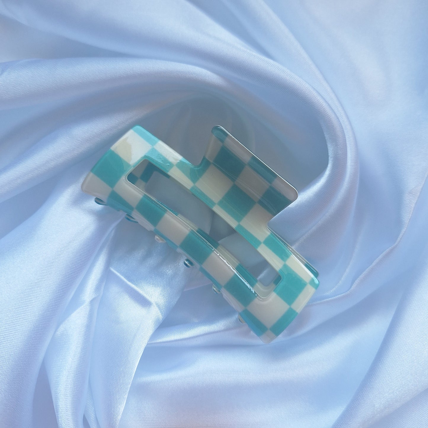 Turquoise and white gingham check hair claw clip on a white satin background.