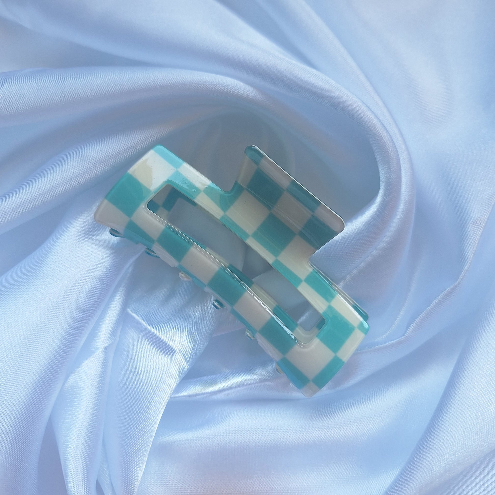 Turquoise and white gingham check hair claw clip on a white satin background.
