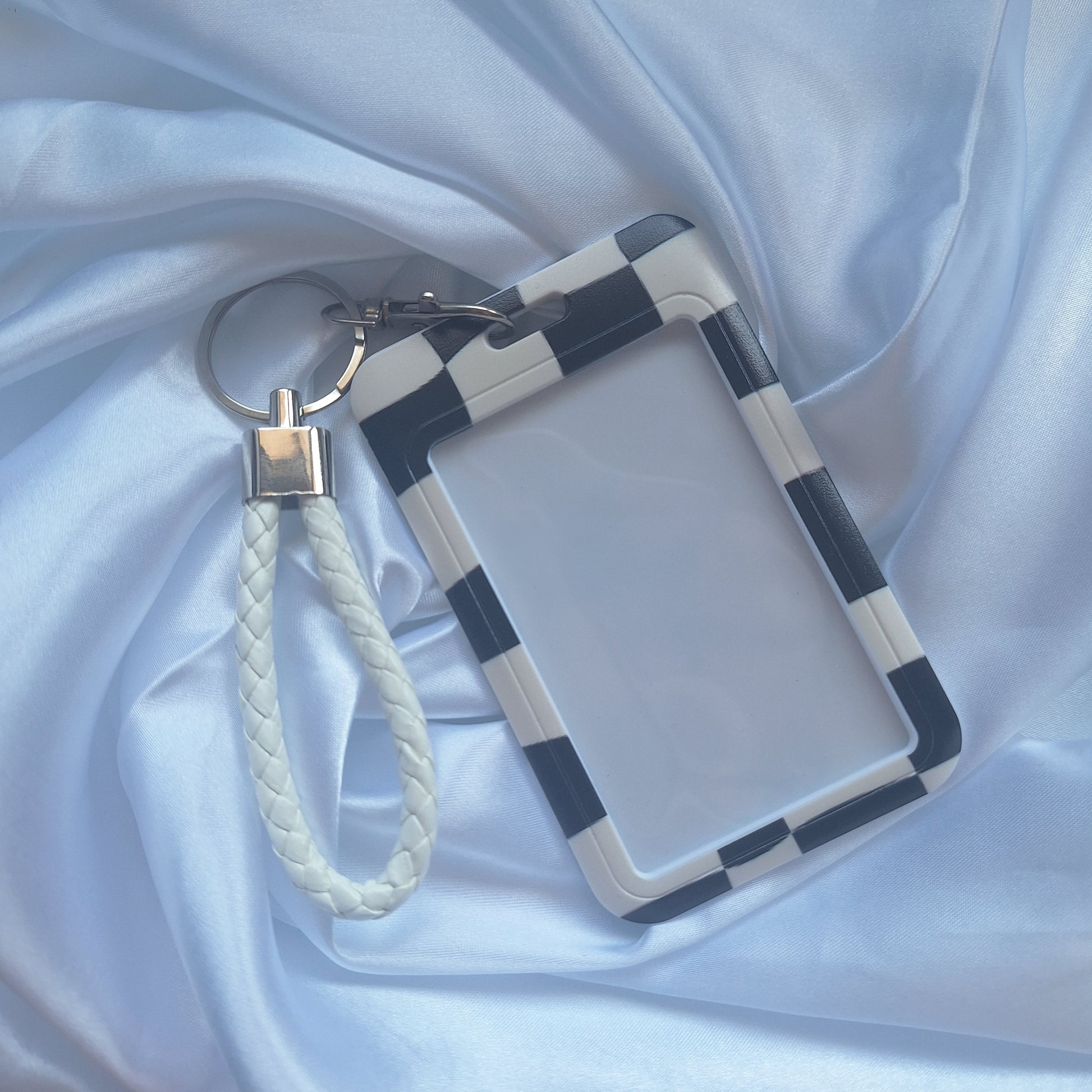 Black and white checkered ID card holder with matching white wrist strap inspired by motorsport racing flags.