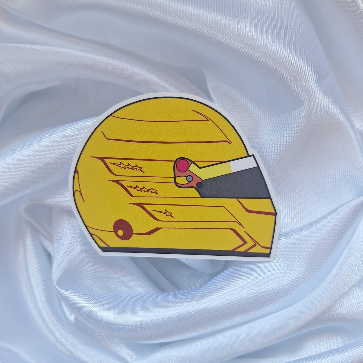 Lewis Hamilton 2026 Formula 1 helmet sticker featuring a vibrant yellow racing helmet design with red accents, star details, and a dark visor on a white background.